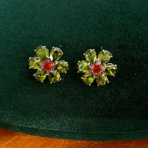 Makroansicht von Vintage-Blumenohrsteckern mit smaragdgrünen und roten Zirkonia-Steinen