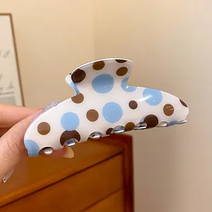 Close-up view of a retro blue and brown polka dot hair claw clip with a glossy finish.