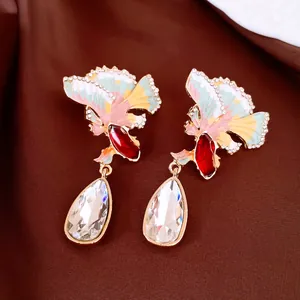 Close-up macro view of Chinese style enamel fan earrings featuring sparkling teardrop crystal pendants