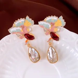 Detail showing colorful enamel fan design and clear teardrop crystals of the earrings