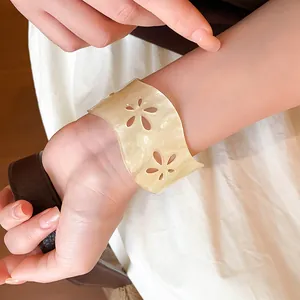 Detailansicht eines cremefarbenen Acryl-Armreifs mit eleganten Blumen-Ausschnitten