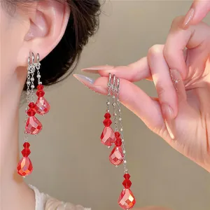 Detailed view of elegant silver tassel drop earrings with vibrant red faceted crystals