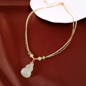 Macro view of a chalcedony gourd pendant on a double-layer 18k gold beaded chain.
