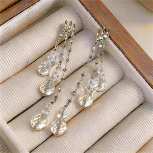 Close-up detail of silver needle multi-layer tassel earrings with clear faceted crystal drops.