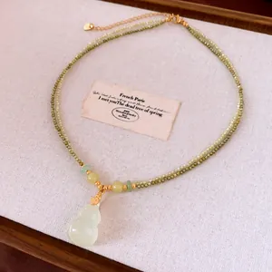Close-up of double-layered beaded necklace with a light green jadeite gourd pendant