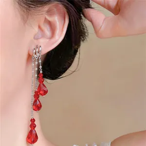 Close-up detail of multi-layer red crystal tassel earrings worn on a female ear.