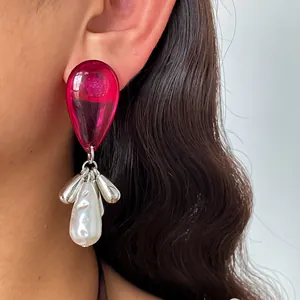Close-up detail of retro magenta acrylic waterdrop earrings with pearl and silver tassels