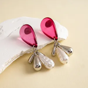 Macro view of vintage pink acrylic drop earrings featuring white textured pearls and silver tassels