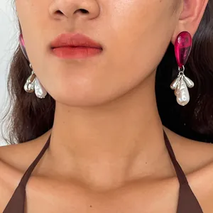 Close-up detail of vintage pink acrylic and pearl teardrop earrings worn by a model