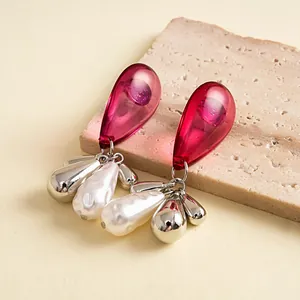 Macro view of vintage acrylic waterdrop earrings with metallic tassels and pearls.