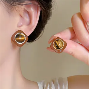 Close-up of vintage brown stud earrings with tiger-eye stone on an Asian model
