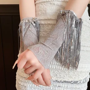 Primo piano dettagliato di manicotti in pizzo grigio con nappe di paillettes su abito bianco