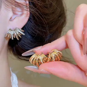 Vue détaillée de boucles d'oreilles en C multicouches avec zircons portées et tenues en main.