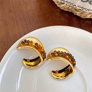 Detailed macro view of vintage gold pleated stud earrings with small brown bead accents