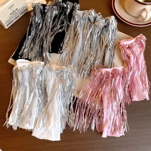 Dettaglio dei polsini con paillettes e frange alla moda in quattro colori su un tavolo.