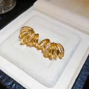 Détail macro de boucles d'oreilles multicouches en forme de C dorées 18K dans leur écrin