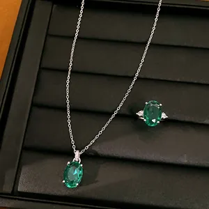 Detailopname van smaragdgroene ovale zirkoon ketting en ring set op zwart plateau