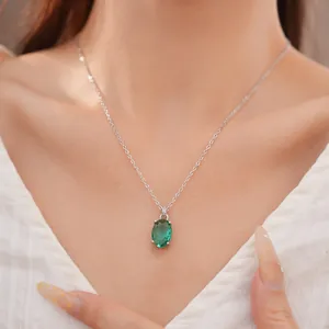Elegante zilverkleurige ketting met een ovale groene zirkoon hanger op een model.