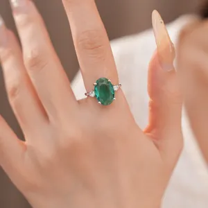 Detailweergave van een elegante zilveren ring met een grote ovale groene zirkoon op vinger.