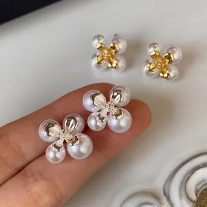 Detailansicht eleganter französischer Vintage-Perlenblumenohrstecker auf einem Finger.
