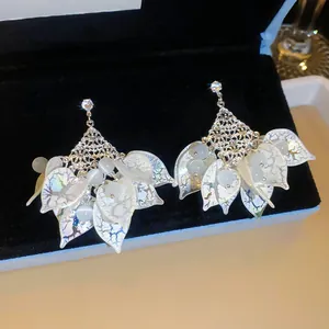 Detailopname van bohemian kwastjes oorbellen met iriserende acryl blaadjes in een luxe doos