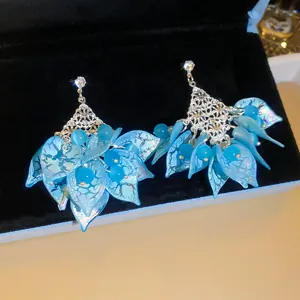 Detail van bohemian oorbellen met blauwe acryl bloembladen en schitterende strass.