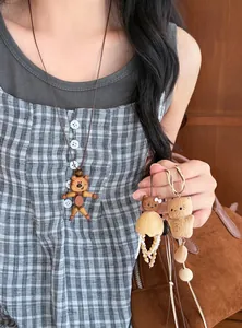 Detailed macro view of vintage wooden bear and cat pendants on long necklaces held by model