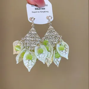 Detailopname van Bohemian oorbellen met groene acryl bloemblaadjes en zilveren ruit