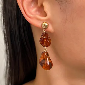 Elegante amberkleurige hars oorbellen in Maillard-stijl op het oor