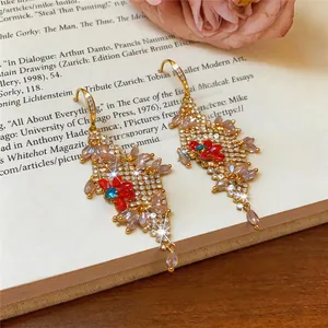 Gedetailleerd zicht op elegante gouden bloemenoorbellen met veel gekleurde strassteentjes
