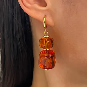 Detailopname van Maillard oorbellen met onregelmatige amberkleurige harskralen.