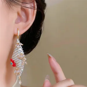 Detailopname van elegante strass-kwastoorbellen met een opvallend rood bloemaccent