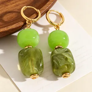 Detailweergave van stijlvolle onregelmatige groene hars kralen oorbellen met gouden ringen