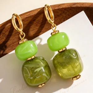 Detail van onregelmatige groene hars oorbellen met dubbele kralen en goudkleur