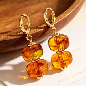 Macro detail van Maillard amberkleurige hars dubbele kraal oorbellen met gouden ringen