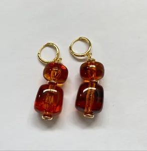 Detail van de amberkleurige harskralen oorbellen in Maillard-stijl met gouden ringen