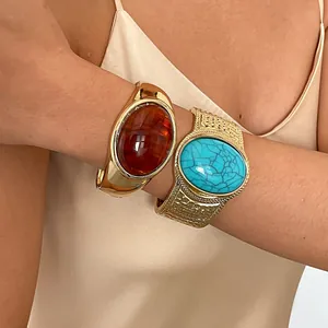 Macro view of chunky retro gold bangles with large amber and turquoise resin stones