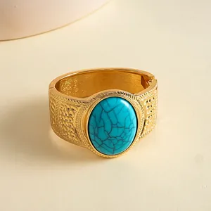 Macro view of a vintage gold metal cuff bracelet with an oval turquoise resin stone.