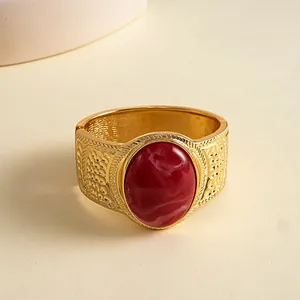 Detailed view of vintage gold bangle featuring large marbled red resin stone center