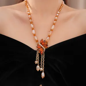 Detailed view of vintage amber beaded necklace with flower pendant and tassels