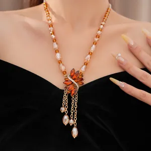 Detailed view of a vintage amber beaded necklace with rhinestone flower and tassels.