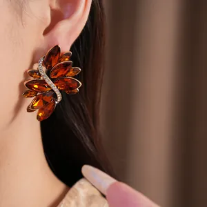 Detail macro view of vintage amber crystal leaf earrings elegantly worn on a model's ear