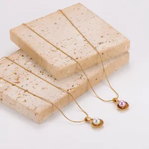 Close-up detail of elegant gold shell necklaces with white and pink pearls on stone blocks