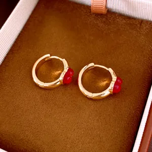 Nahaufnahme von Vintage Gold-Ohrringen mit roten Blumenanhängern in einer Box