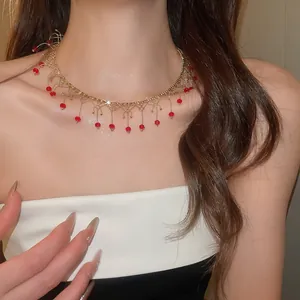 Détail du ras de cou en dentelle dorée avec glands en perles de cristal rouge