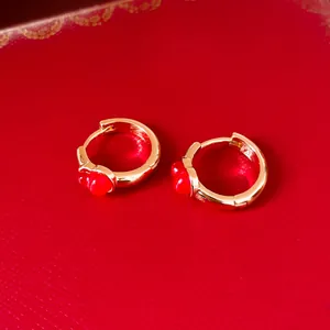 Detailansicht von goldenen Vintage-Creolen mit zarten roten Emaille-Blumenakzenten.
