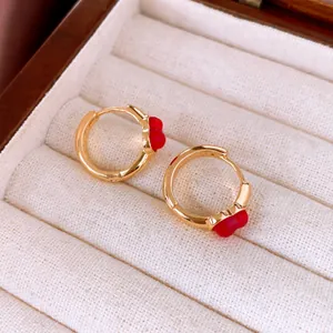 Detailaufnahme goldener Vintage-Creolen mit roten Emaille-Blumen in einer Schmuckschatulle.