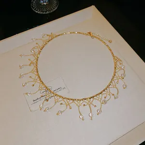 Vue détaillée du collier en dentelle dorée et cristal avec pendentifs scintillants.