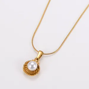 Detailed close-up of a gold shell pendant with a white pearl on a delicate chain