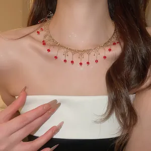 Vue détaillée d'un collier choker en dentelle dorée avec des pampilles de perles rouges